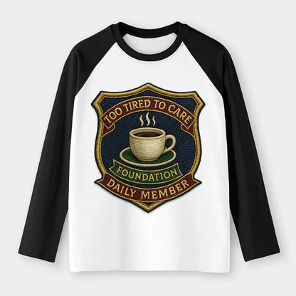 Crest with coffee cup - "Too Tired To Care Foundation - Daily Member" - Raglan Long Sleeve T-Shirt - Black