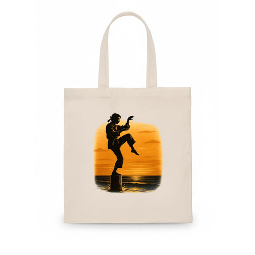 karate crane kick pose on wooden post at beach sunset - Tote Bag